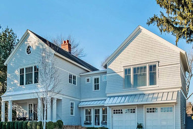 Aménagement d'une grande façade de maison grise classique à un étage avec un revêtement en vinyle, un toit en appentis et un toit en métal.