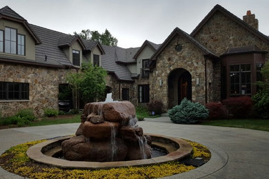 Large 1960s brown two-story stone house exterior idea in Denver with a hip roof and a tile roof