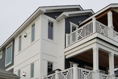Ejemplo de fachada de casa multicolor marinera grande de tres plantas con revestimientos combinados, tejado a doble faldón y tejado de teja de madera