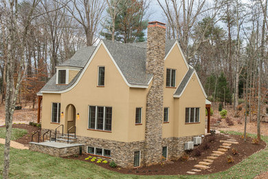Mid-sized transitional beige one-story stone exterior home idea in Other with a clipped gable roof