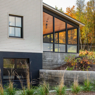 Imagen de fachada de casa beige, de estilo de casa de campo, de tamaño medio, de tres plantas, con revestimiento de hormigón, tejado a dos aguas y tejado de metal