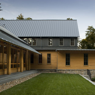 Modelo de fachada de casa marrón, tradicional renovada, de dos plantas, con revestimiento de madera y tejado de metal