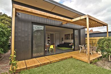Medium sized and black urban bungalow house exterior in Melbourne with metal cladding and a flat roof.
