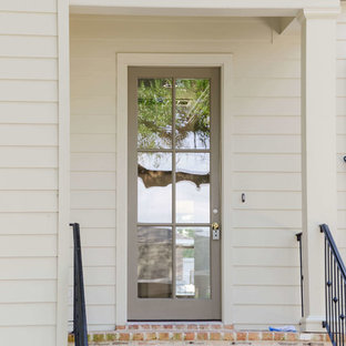 Idées déco pour une grand façade de maison beige classique à un étage avec un revêtement en panneau de béton fibré et un toit à deux pans.