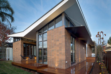 Modelo de fachada de casa marrón contemporánea de tamaño medio de una planta con revestimiento de ladrillo y tejado de metal