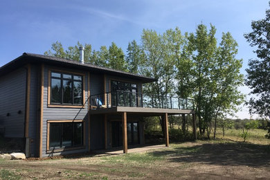 Example of a trendy gray concrete fiberboard house exterior design in Calgary with a tile roof