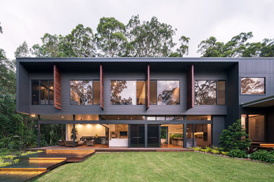 Modelo de fachada de casa negra contemporánea de tamaño medio de dos plantas con revestimiento de aglomerado de cemento, tejado plano y tejado de metal