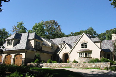Imagen de fachada de casa beige clásica de tamaño medio de dos plantas con revestimientos combinados, tejado a dos aguas y tejado de teja de madera