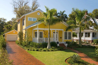 Imagen de fachada de casa amarilla marinera de tamaño medio de dos plantas con revestimiento de madera, tejado a dos aguas y tejado de teja de madera