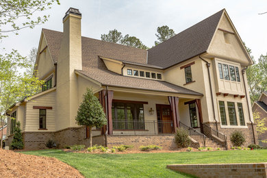 Arts and crafts beige two-story stucco house exterior photo in Charlotte with a shingle roof