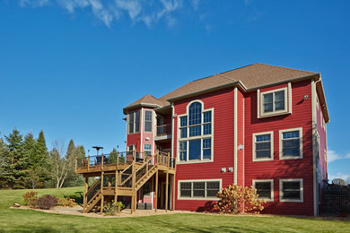 Large elegant red two-story wood exterior home photo in Other with a shingle roof
