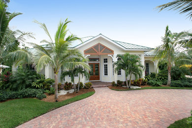 Diseño de fachada de casa blanca costera de tamaño medio de una planta con revestimiento de estuco, tejado a cuatro aguas y tejado de metal
