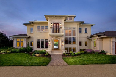 Large trendy beige two-story concrete house exterior photo in Other with a clipped gable roof and a shingle roof