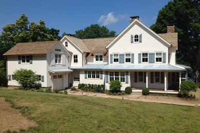 This is an example of a white country two floor house exterior in Bridgeport with wood cladding.