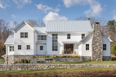 На фото: большой, двухэтажный, белый частный загородный дом в стиле кантри с комбинированной облицовкой, двускатной крышей и металлической крышей с