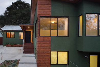 Cette photo montre une façade de maison verte moderne en stuc de taille moyenne et de plain-pied avec un toit en appentis.