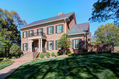 Inspiration for a large timeless red two-story brick exterior home remodel in Charlotte with a hip roof