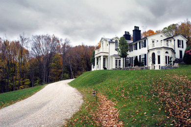 Cette image montre une très grande façade de maison blanche en bois avec un toit à deux pans.