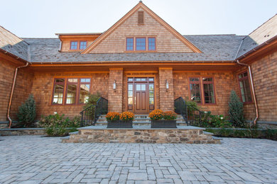 Modelo de fachada de casa marrón costera grande de dos plantas con revestimiento de madera, tejado a dos aguas y tejado de teja de madera