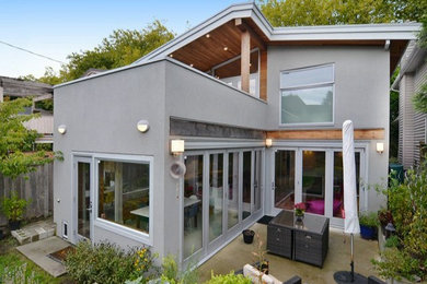 Inspiration pour une grande façade de maison grise design en stuc à un étage avec un toit à deux pans.
