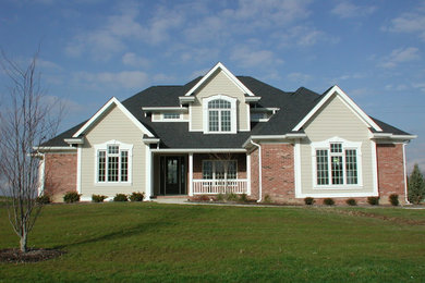 Example of a mid-sized classic beige two-story brick exterior home design in Other