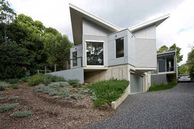Ejemplo de fachada gris minimalista de tamaño medio de dos plantas con revestimiento de metal y tejado de un solo tendido