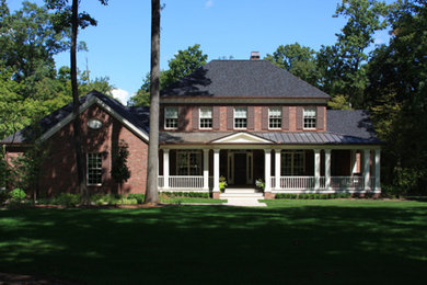 Imagen de fachada de casa roja tradicional grande de dos plantas con revestimiento de piedra y tejado a la holandesa