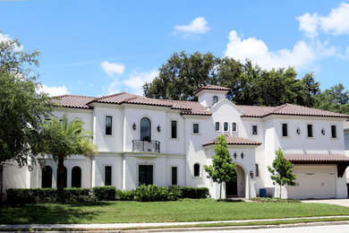 Huge mediterranean white two-story stucco house exterior idea in Tampa with a hip roof and a tile roof