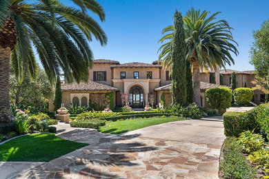 Example of a tuscan beige two-story house exterior design in Orange County with a hip roof and a tile roof