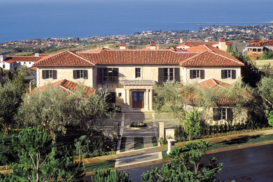 Inspiration for a huge mediterranean beige two-story stone house exterior remodel in Los Angeles with a hip roof and a tile roof