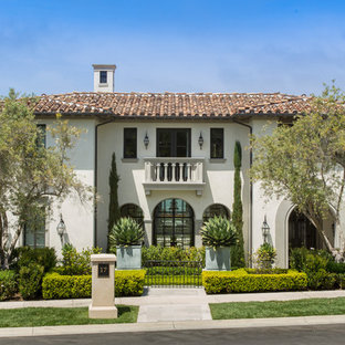 Example of a large tuscan beige three-story stone house exterior design in Orange County with a tile roof and a hip roof