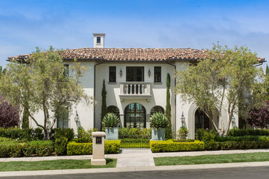 Example of a large tuscan beige three-story stone house exterior design in Orange County with a tile roof and a hip roof