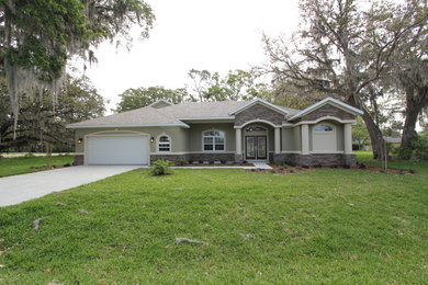 Large transitional green two-story stone exterior home photo in Orlando with a shingle roof