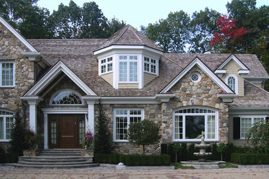 Large traditional beige two-story stone house exterior idea in Boston with a shingle roof