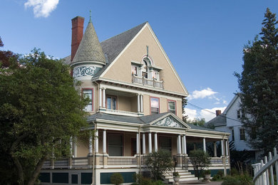 Foto della villa grande beige vittoriana a tre piani con rivestimento in legno, tetto a capanna e copertura a scandole