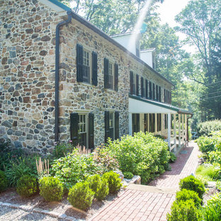 Imagen de fachada de casa de estilo de casa de campo, grande, de tres plantas, con revestimiento de piedra, tejado a dos aguas y tejado de metal