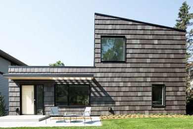 Inspiration pour une façade de maison grise design à un étage avec un toit plat et un toit en tuile.