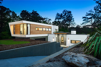 Foto de fachada de casa blanca moderna de tamaño medio de tres plantas con revestimientos combinados y tejado plano