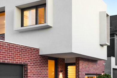 Modelo de fachada de casa multicolor moderna pequeña de dos plantas con revestimiento de ladrillo y tejado plano
