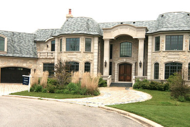 Imagen de fachada beige clásica extra grande de dos plantas con revestimiento de piedra y tejado a cuatro aguas