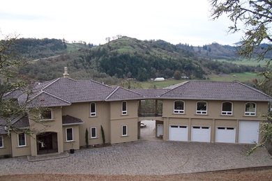 Example of a large classic beige two-story stucco house exterior design in Portland with a clipped gable roof and a tile roof