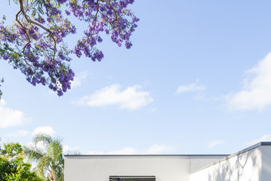 Mittelgroßes, Zweistöckiges Modernes Haus mit Putzfassade, weißer Fassadenfarbe und Flachdach in Sydney