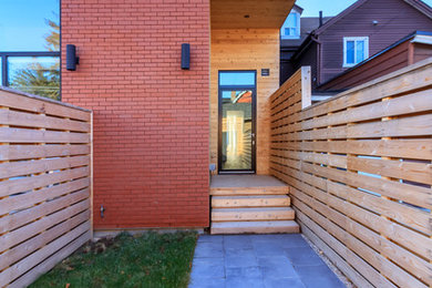 Medium sized and red contemporary brick house exterior in Toronto with three floors and a flat roof.