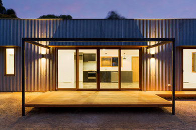 Diseño de fachada de casa gris actual de tamaño medio de una planta con revestimiento de metal, tejado plano y tejado de metal