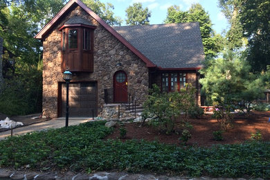 Large rustic brown two-story stone gable roof idea in New York