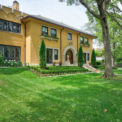 Example of a large ornate yellow two-story brick house exterior design with a hip roof and a tile roof