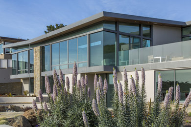 Inspiration pour une très grande façade de maison grise minimaliste en béton à un étage avec un toit plat.