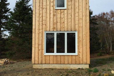 Imagen de fachada moderna pequeña de dos plantas con revestimiento de madera y tejado a dos aguas