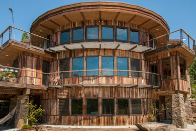 Foto de fachada de casa marrón rural grande de tres plantas con revestimiento de madera, tejado plano y techo verde