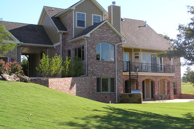 Photo of a large and red classic two floor brick house exterior in Oklahoma City with a pitched roof.